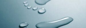 Two wet footprints made from water droplets are shown on a smooth, light blue surface.