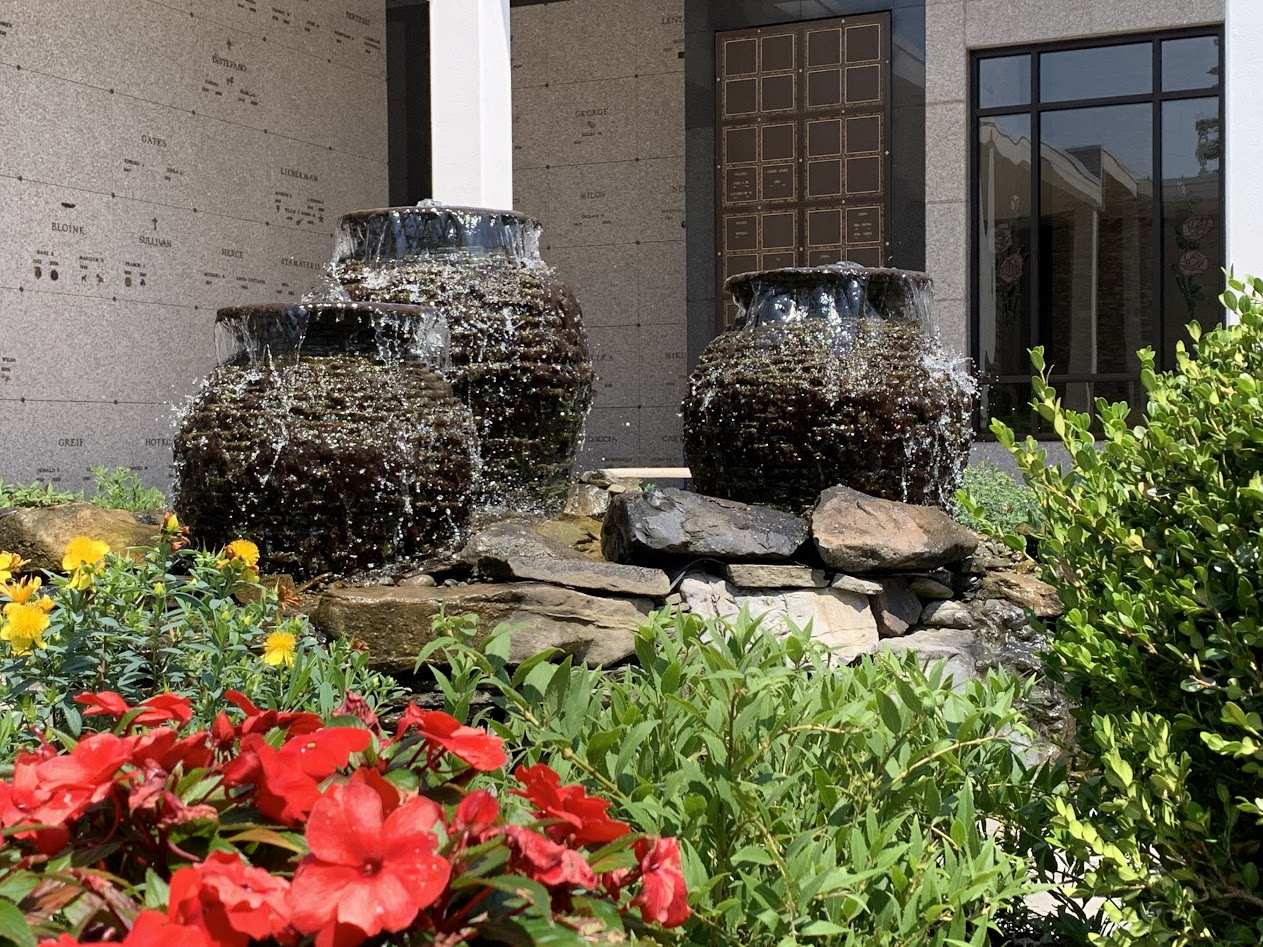 Pots with water pouring out of them surrounded by flowers