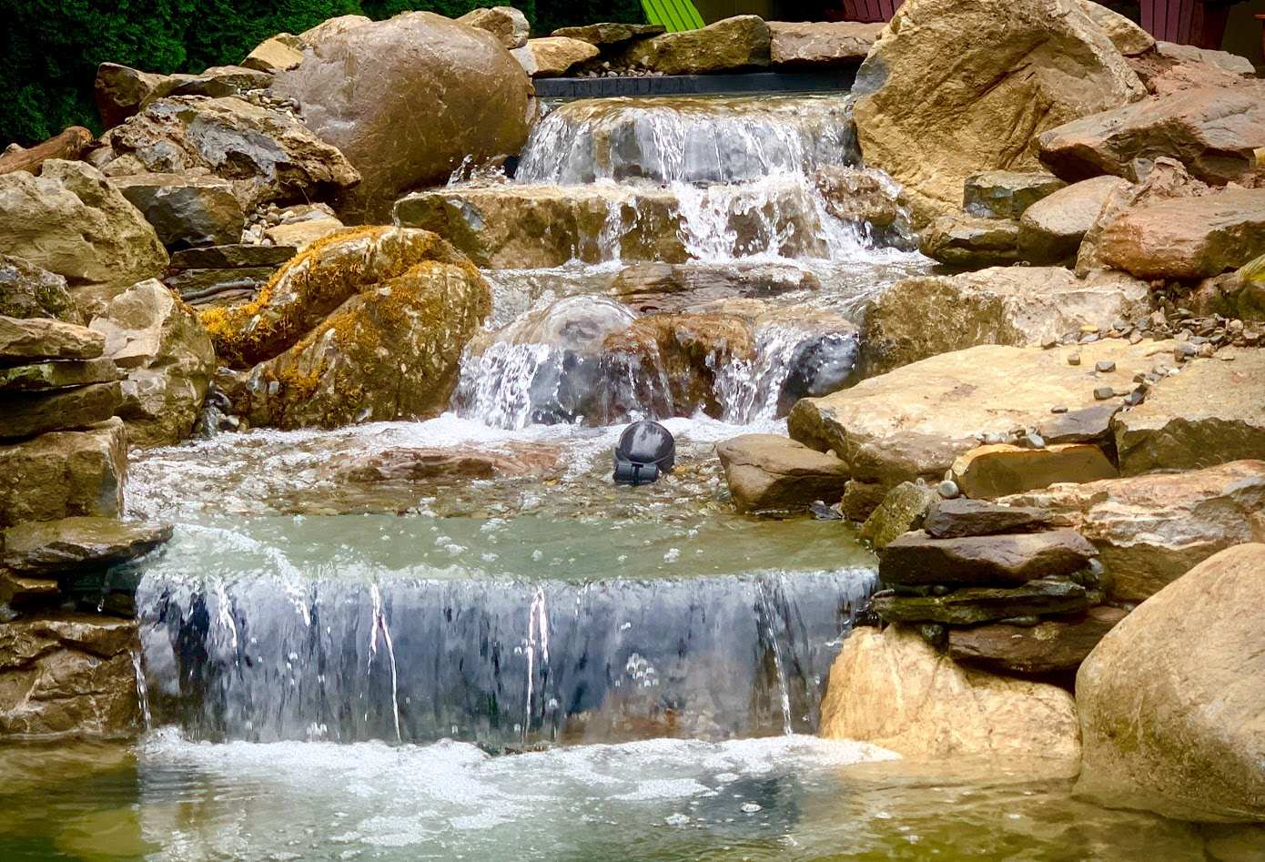 Beautiful waterfall surrounded by rocks design by That Pond Place