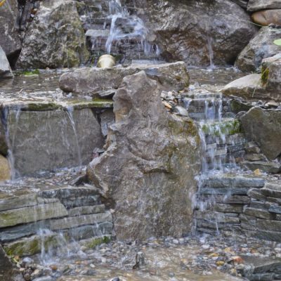 Water cascades down a series of stone steps in a landscaped rock waterfall and garden.