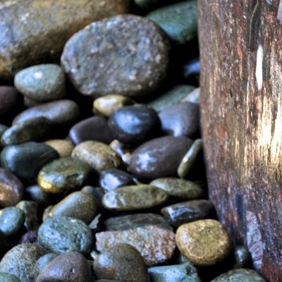 Smooth river rocks and a large weathered stone illuminated by natural light.